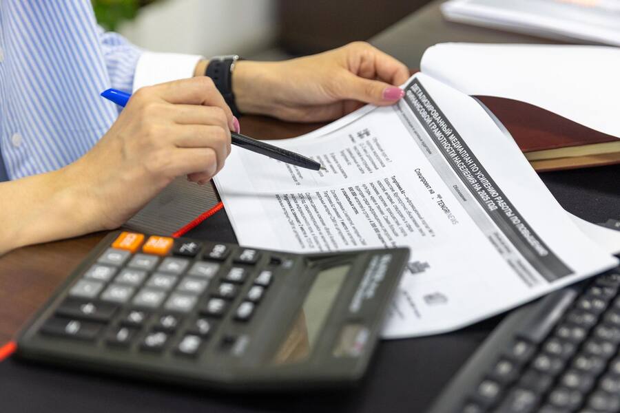 Profissional de contabilidade conferindo documentos com calculadora
